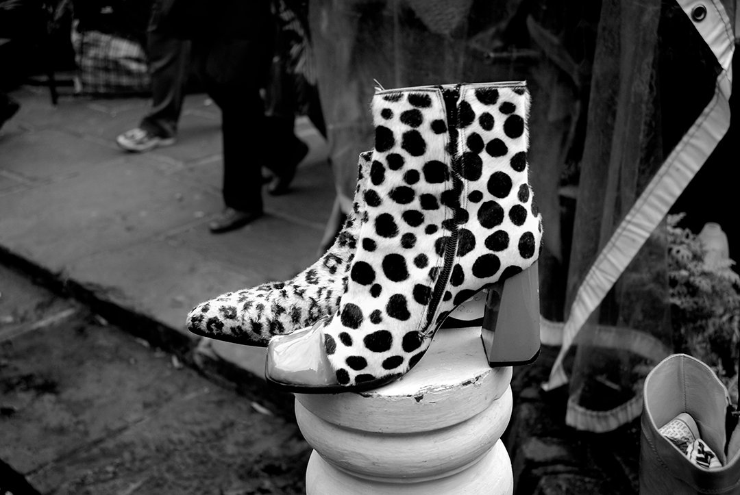 Polka-dot ankle boots on display beside a street with passing pedestrians.